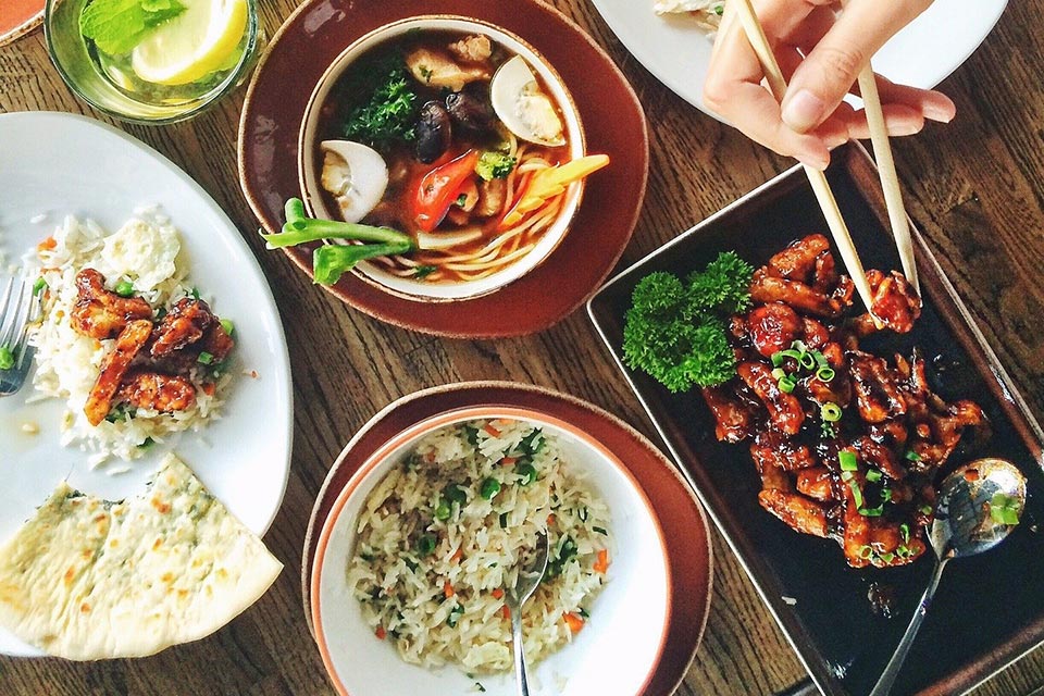 Chinese food with hands holding chopsticks