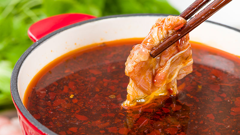 Chinese hot pot with chopsticks holding beef